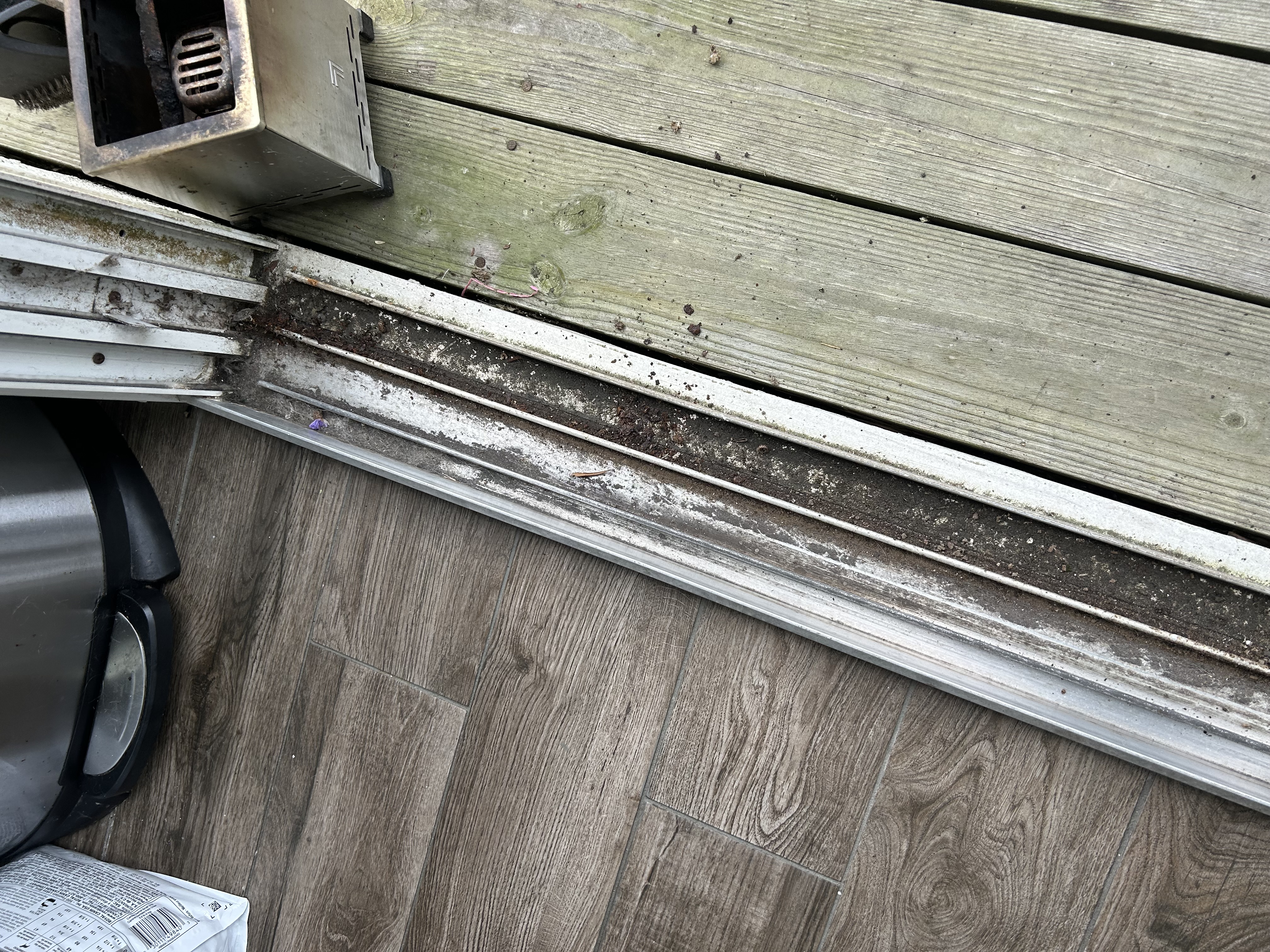 Sliding door track packed with dirt, debris, and corrosion